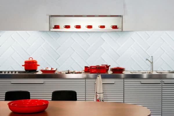 How to tile a kitchen splashback wall - A light blue kitchen splashback wall with distinct red pots and pans